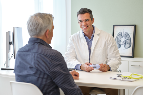 Man sitting in front of a doctor holding an EasyOne Sky